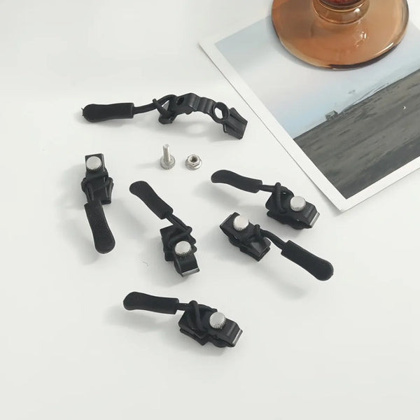 A black universal zipper repair kit with replacement heads and small metal components displayed on a white surface.