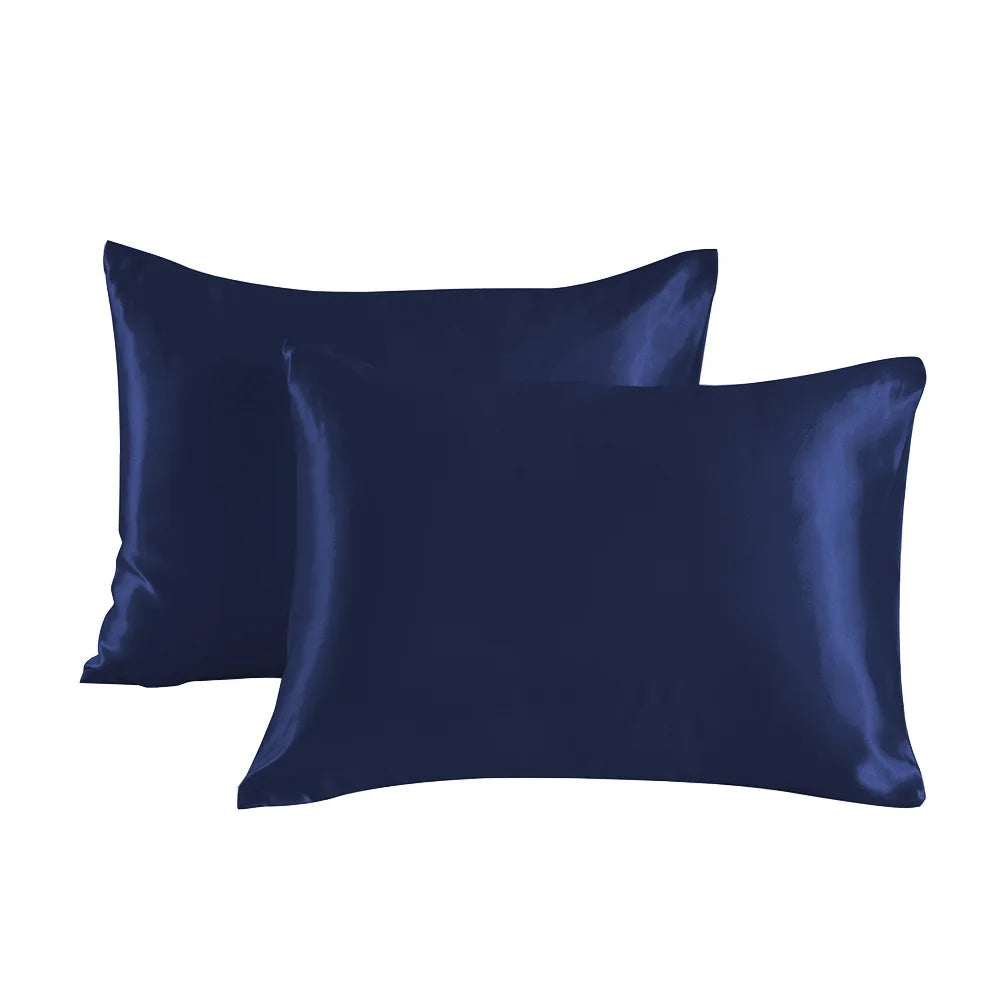 A pair of dark navy blue satin pillowcases lying flat.