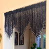 Elegant black lace curtain valance hanging over a window with silver fringe details.
