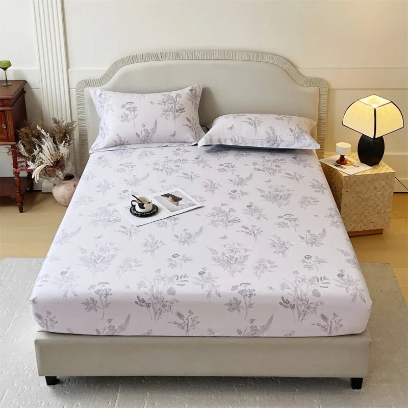 A white floral printed cotton fitted sheet is displayed on a bed with matching pillows and bedding.