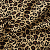 A close-up of a luxury leopard print fabric in shades of brown and beige, draped and folded.