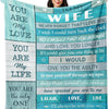 A woman holds up a blue and teal printed throw blanket with text about love and life.