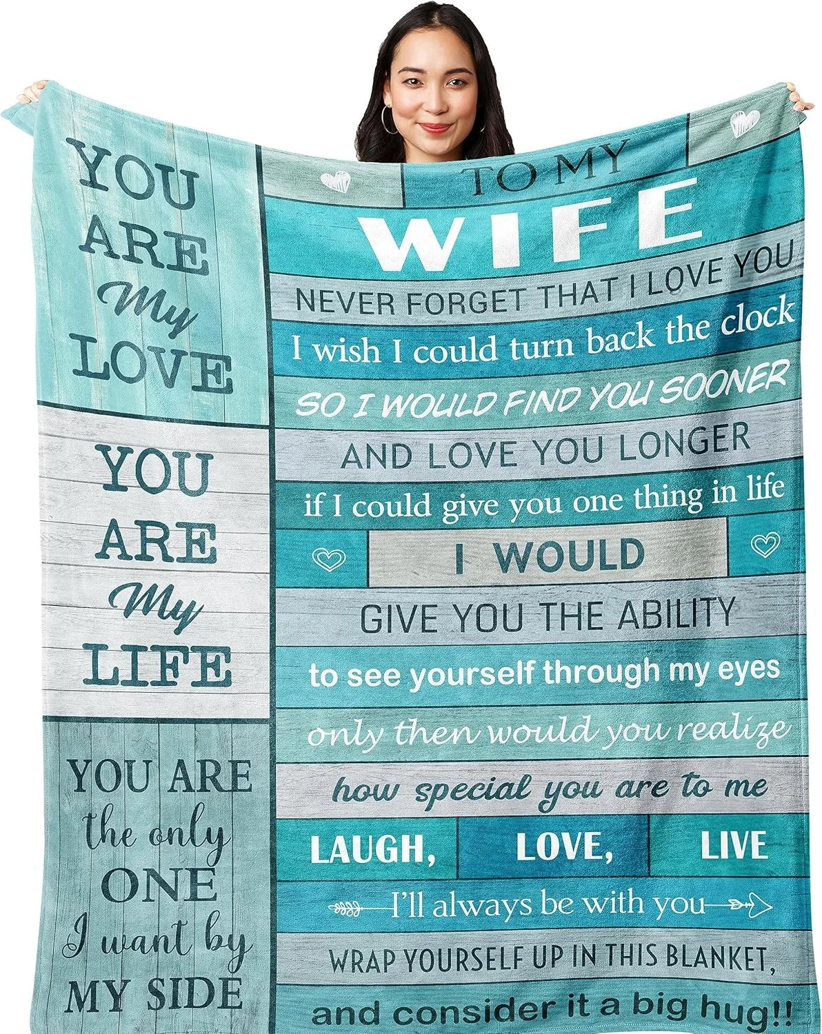 A woman holds up a blue and teal printed throw blanket with text about love and life.
