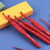 A set of red ergonomic crochet hooks resting on a yellow wooden block.
