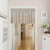 A white door with a sheer linen crochet half curtain in beige and white patterns.