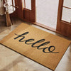 A rectangular woven doormat with the word hello written in black script on a natural tan background.
