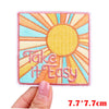 A square embroidered patch featuring a yellow sun with the text Take It Easy in pink thread.