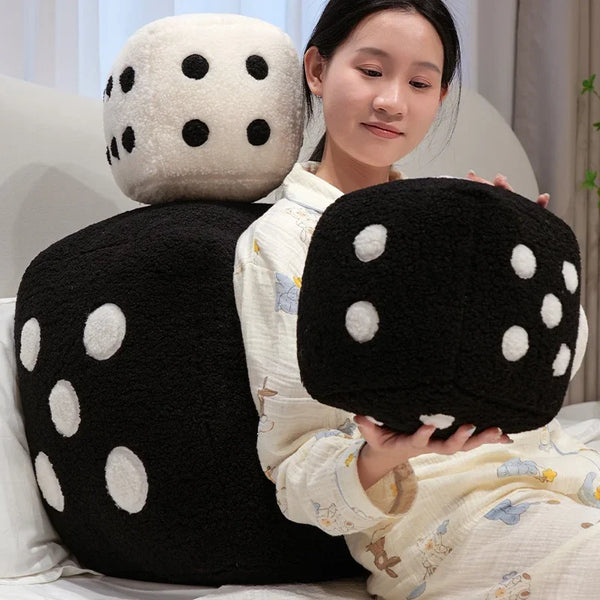 A woman is holding a large black and white polka-dotted plush dice shaped pillow.