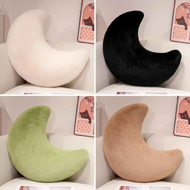 Four moon-shaped throw pillows in white, black, green, and beige displayed in a box.