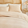 Beige plaid quilt set featuring a quilted duvet and pillows on a light wood headboard.
