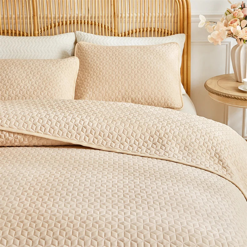 Beige plaid quilt set featuring a quilted duvet and pillows on a light wood headboard.