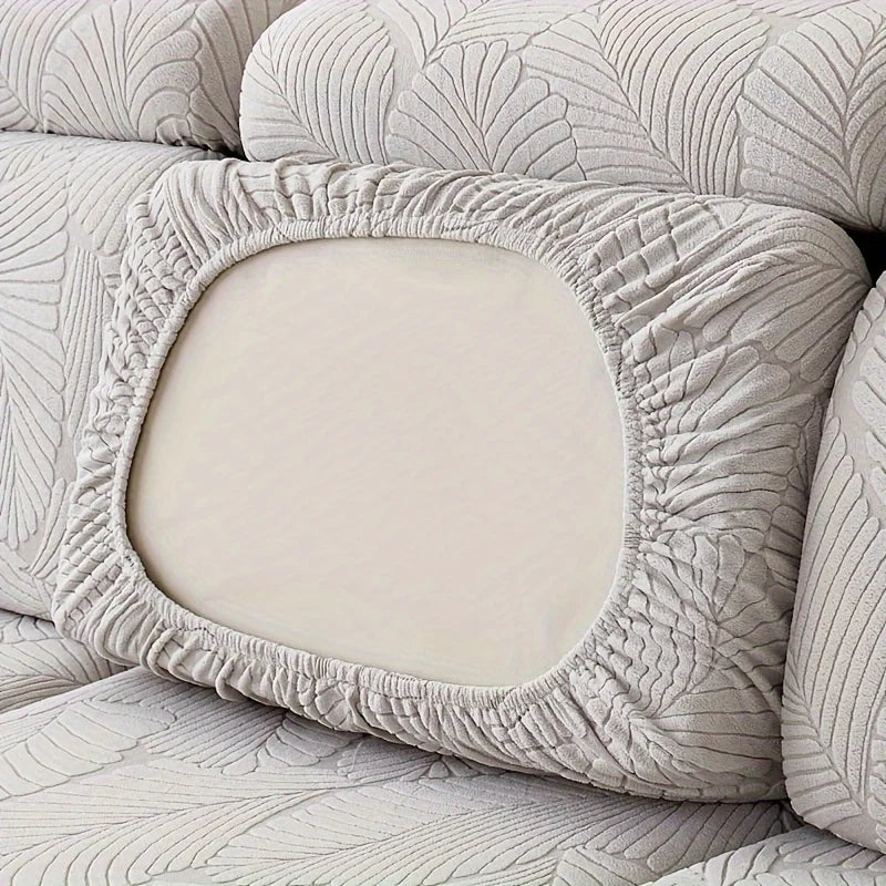 A close-up of a light beige luxury leaf pattern sofa slipcover with a decorative oval insert.