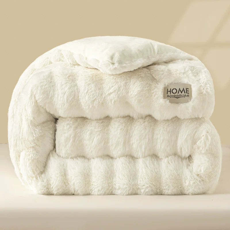 A fluffy white rabbit quilt comforter folded neatly on a light surface.