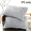 A stack of gray faux fur pillow covers displayed on a wooden chair.