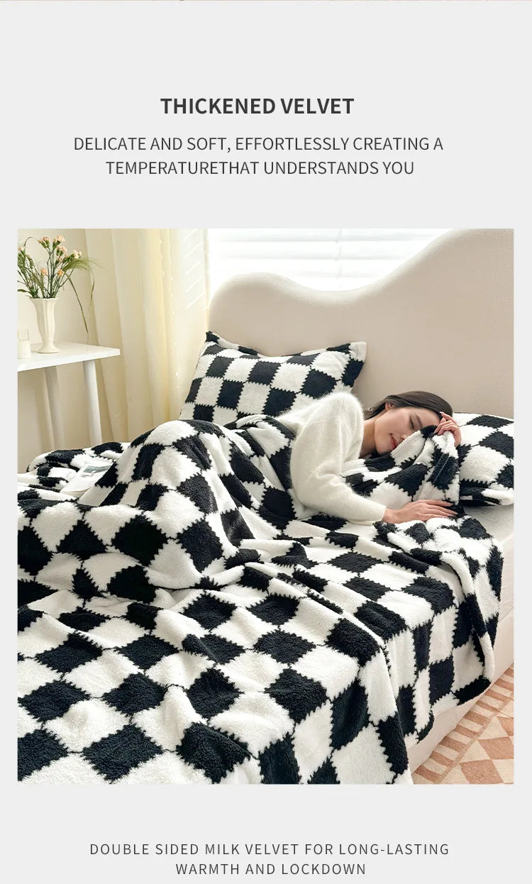 A black and white checkered thick velvet blanket draped over a white bed, with a person resting under it.