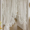 White sheer curtain with ruffled lace trim and vintage floral design hanging in a doorway.