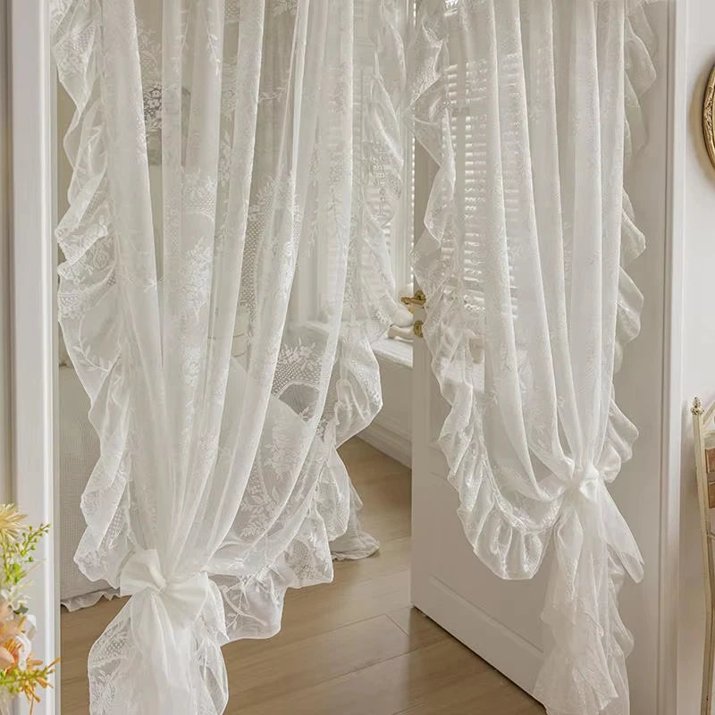 White sheer curtain with ruffled lace trim and vintage floral design hanging in a doorway.