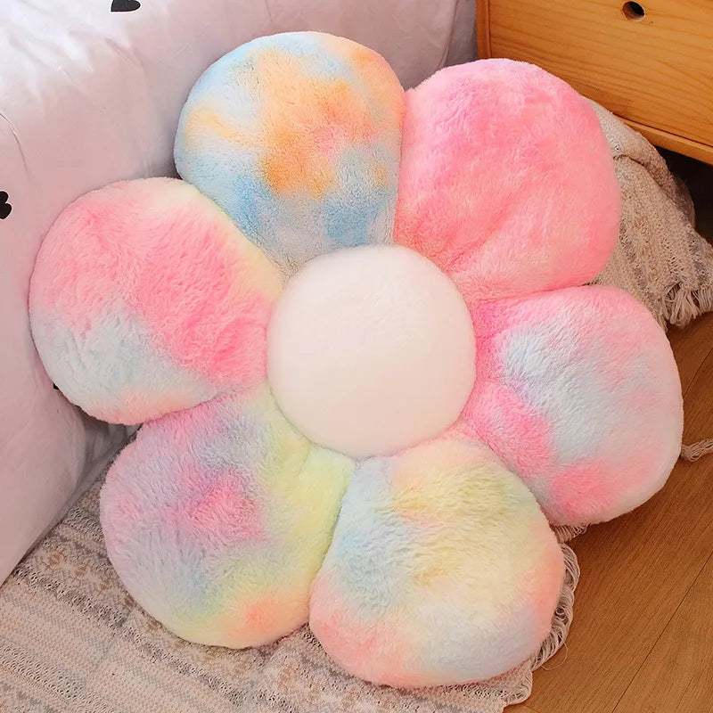 A collection of fluffy, round plush flowers in pastel pinks, blues, and yellows arranged on a light fabric.