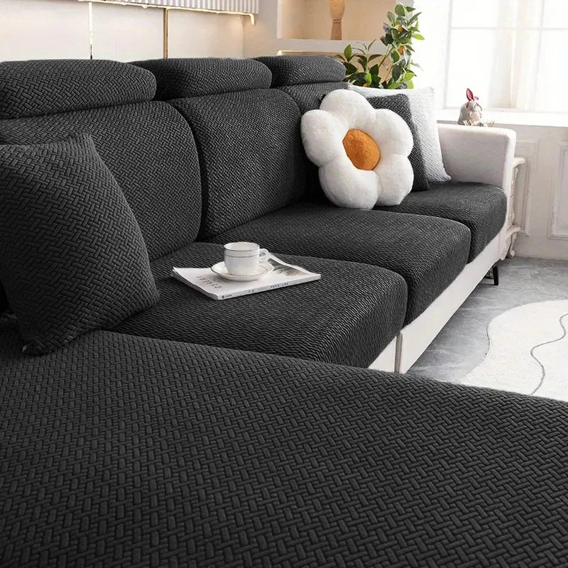 A dark gray thick jacquard sofa seat cushion cover with a white decorative pillow and a cup on the fabric.