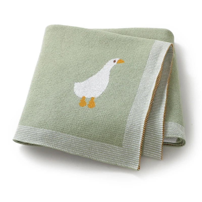 A folded light green cotton blanket with a white duck silhouette on it.