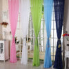 A collection of elegant silver star tulle curtains in pink, white, lime green, blue, and navy hanging in a window.