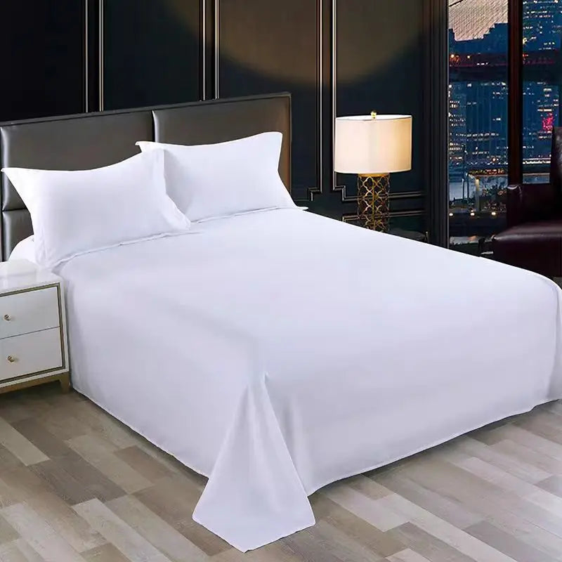White premium flat bed sheet spread on a bed with dark headboard and bedside lamp.