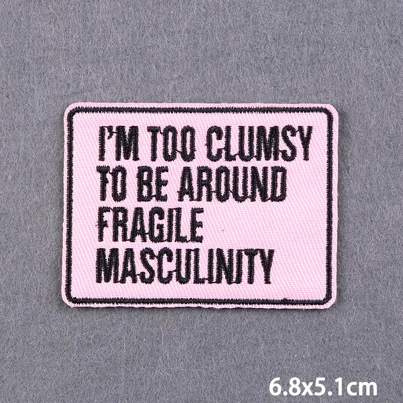A pink embroidered patch with black text that reads I'm too clumsy to be around fragile masculinity