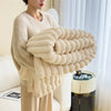 A beige ultra-soft plush winter blanket is draped over a person, showcasing its fluffy texture.
