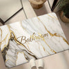 A rectangular door mat featuring a white marble pattern with gold veining and the text Bathroom Just In Lux