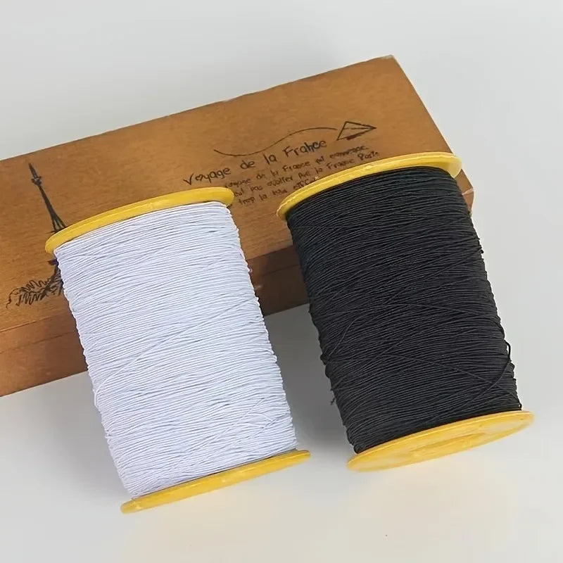 Spool of black elastic sewing thread in a wooden holder resting on a brown box.