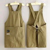 A khaki water-resistant kitchen apron with adjustable straps hanging on a wooden hanger.