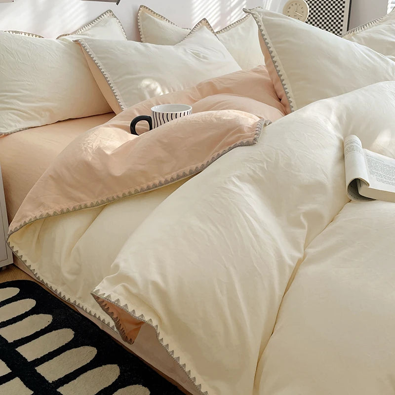 A close-up of a beige and blush pink luxurious washed cotton bed linen set featuring pillows and a duvet.