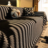A close-up of a black and white herringbone chenille sofa cover with tassel fringes and decorative pillows.