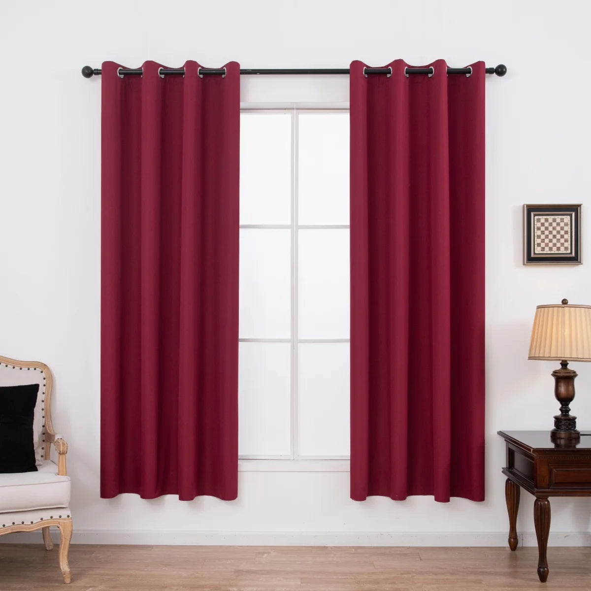 A set of two maroon blackout grommet curtains hanging on a window frame.