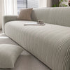 A light beige protective anti-scratch sofa slipcover with textured fabric and throw pillows on a modern sofa.