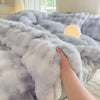 A hand is touching a fluffy gray and white rabbit fleece duvet cover on a bed.