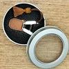Mini precision sewing scissors with a brown leather cover and white grip, resting on a wooden surface.
