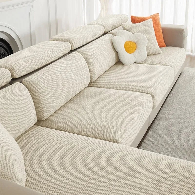 A beige jacquard elastic sofa cushion slipcover with decorative round pillows on a light-colored sofa.