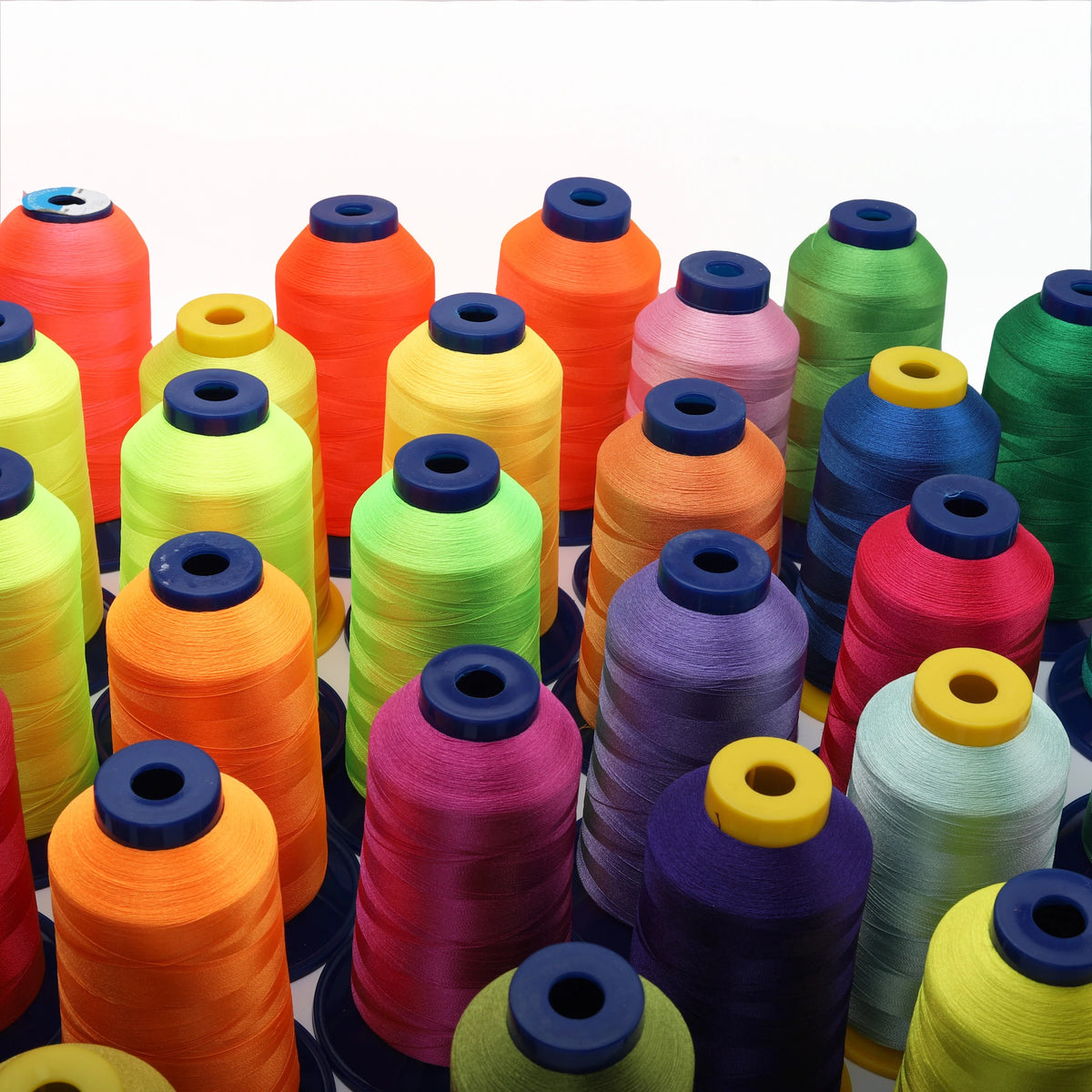 A collection of bright orange, yellow, green, and purple polyester embroidery threads in various spools.