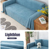 A light blue waterproof sofa cover blanket draped over a modern sofa and displayed next to a wooden tray.