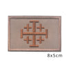 A rectangular embroidered patch featuring a stylized cross design in brown thread on a beige fabric background.