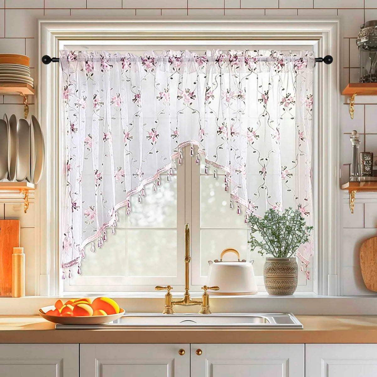 A window decorated with sheer floral embroidery lace curtains and a white ceramic teapot on a kitchen windowsill.