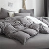 A gray duvet cover set with pom-pom decoration on a bed.