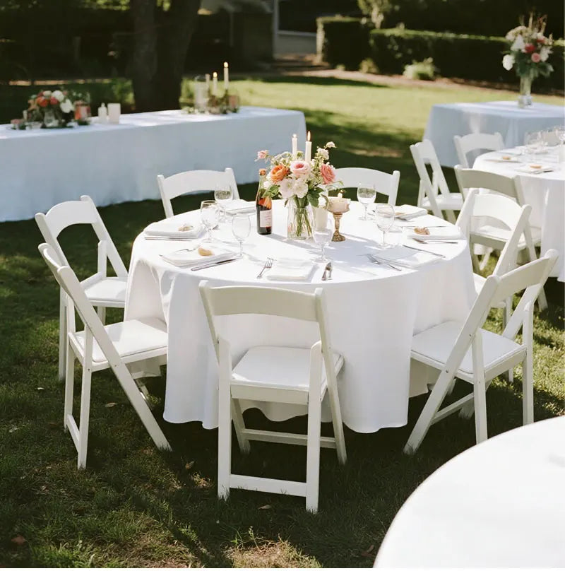 White elegant satin round tablecloths set up outdoors for an event.