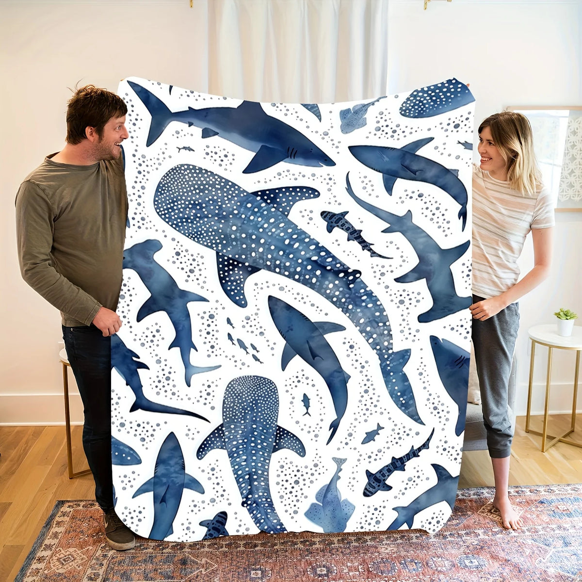 A plush blanket featuring a watercolor pattern of various whale sharks in shades of blue and white.