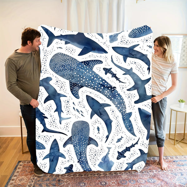 A plush blanket featuring a watercolor pattern of various whale sharks in shades of blue and white.