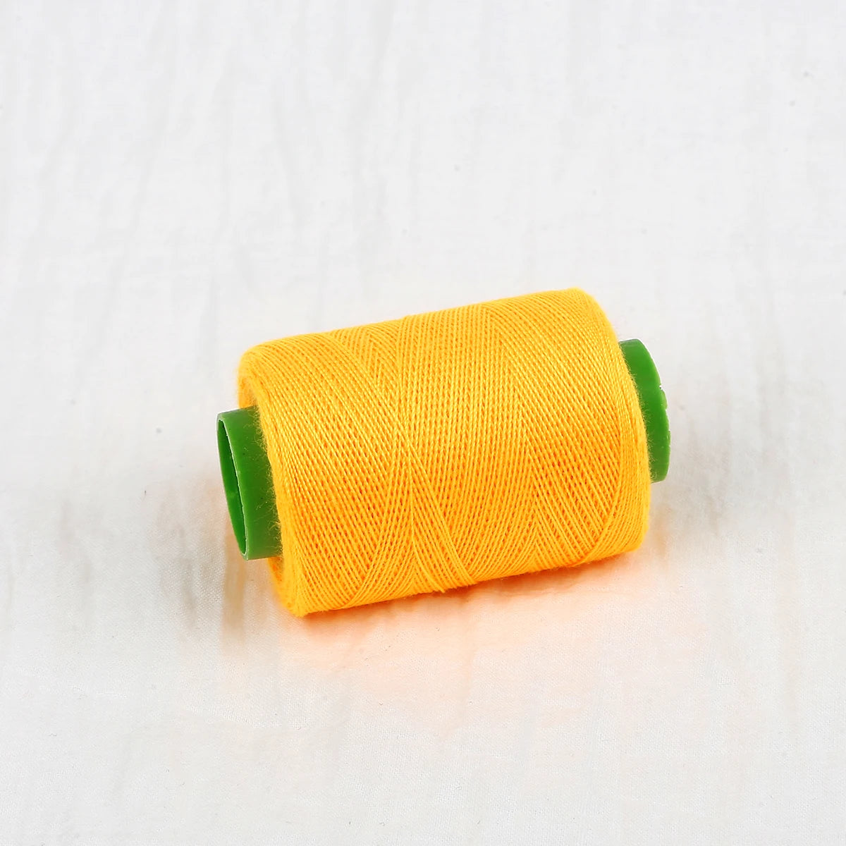 A spool of bright orange sewing thread with green plastic caps.