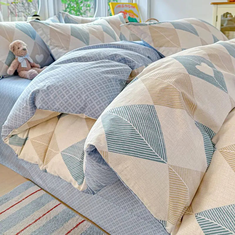 A set of light blue and beige patterned cotton duvet covers and pillows on a bed.