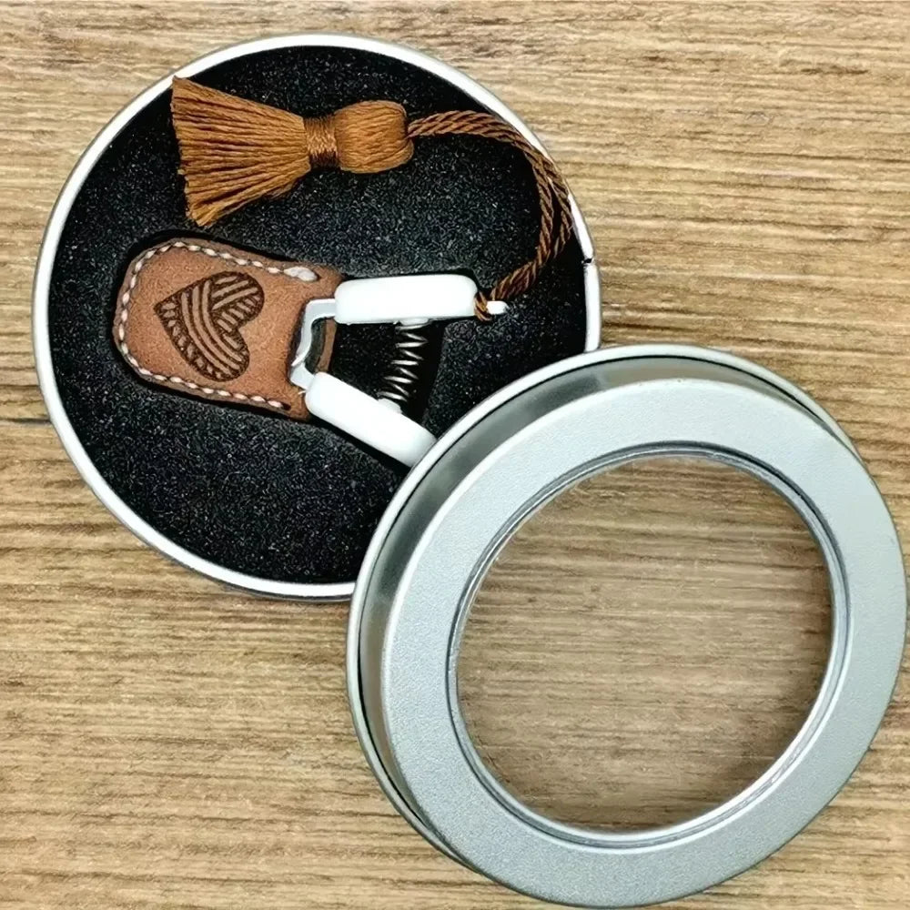 Mini precision sewing scissors with a brown leather cover and white grip, resting on a dark surface.