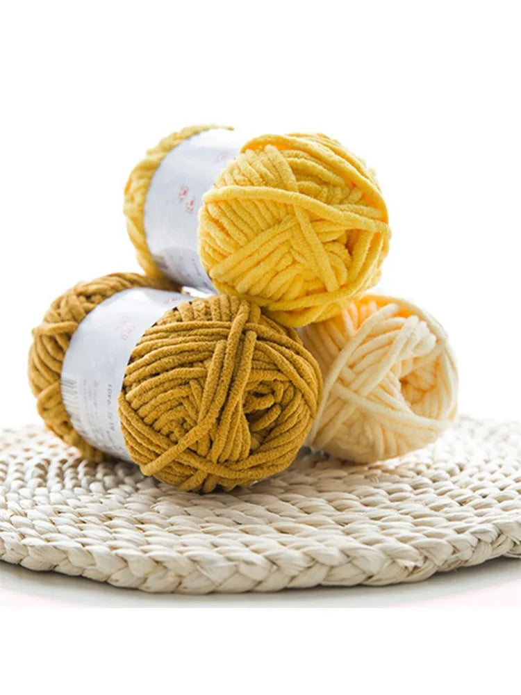 A stack of thick, golden yellow velvet yarn balls wrapped in white labels resting on a woven mat.